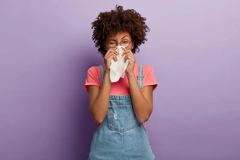 a person sneezing into a tissue